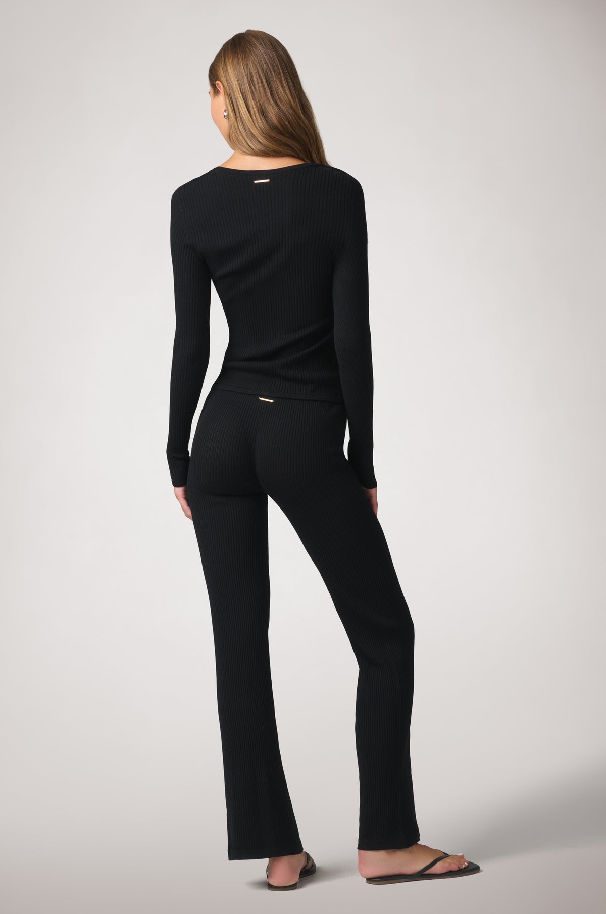 The pants maintain a smooth, fitted look through the seat and hips, with the wide-leg cut continuing through the hem for an elongated silhouette.